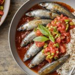 Sardinha na panela de pressão simples e fácil, servida em um prato com molho de tomate e salsinha, acompanhada de arroz branco.